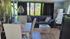 Un salon comprenant un canapé, une table basse, une table à manger avec des chaises et une lampe.