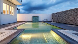 A rooftop swimming pool with a view of the sky and a stone wall. - Diamond Blue Poll Villa D4bhk Luxurious Vegfood (Doddaballapur)