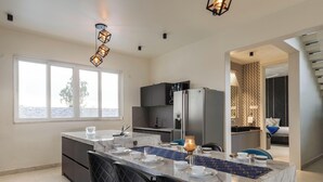 A modern kitchen with a marble island, black chairs, and a patterned backsplash. - Diamond Blue Poll Villa D4bhk Luxurious Vegfood (Doddaballapur)