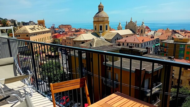 A balcony with a view of a coastal town, including buildings with domed roofs and a prominent church. - Vacation rental with breathtaking ocean views, two minutes from the beaches (Finale Ligure)