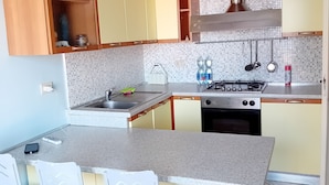 A kitchen with a central island, bar stools, a stove, and a sink. - Vacation rental with breathtaking ocean views, two minutes from the beaches (Finale Ligure)