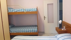A bunk bed room with a door, a bedside table with a lamp, and a striped bedspread. - Vacation rental with breathtaking ocean views, two minutes from the beaches (Finale Ligure)