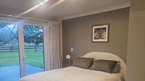 A bedroom with a bed, a picture on the wall, and a view of the outdoors. - Hamilton 3 bedroom Home overlooking paddocks 4 m from city (Tamahere)
