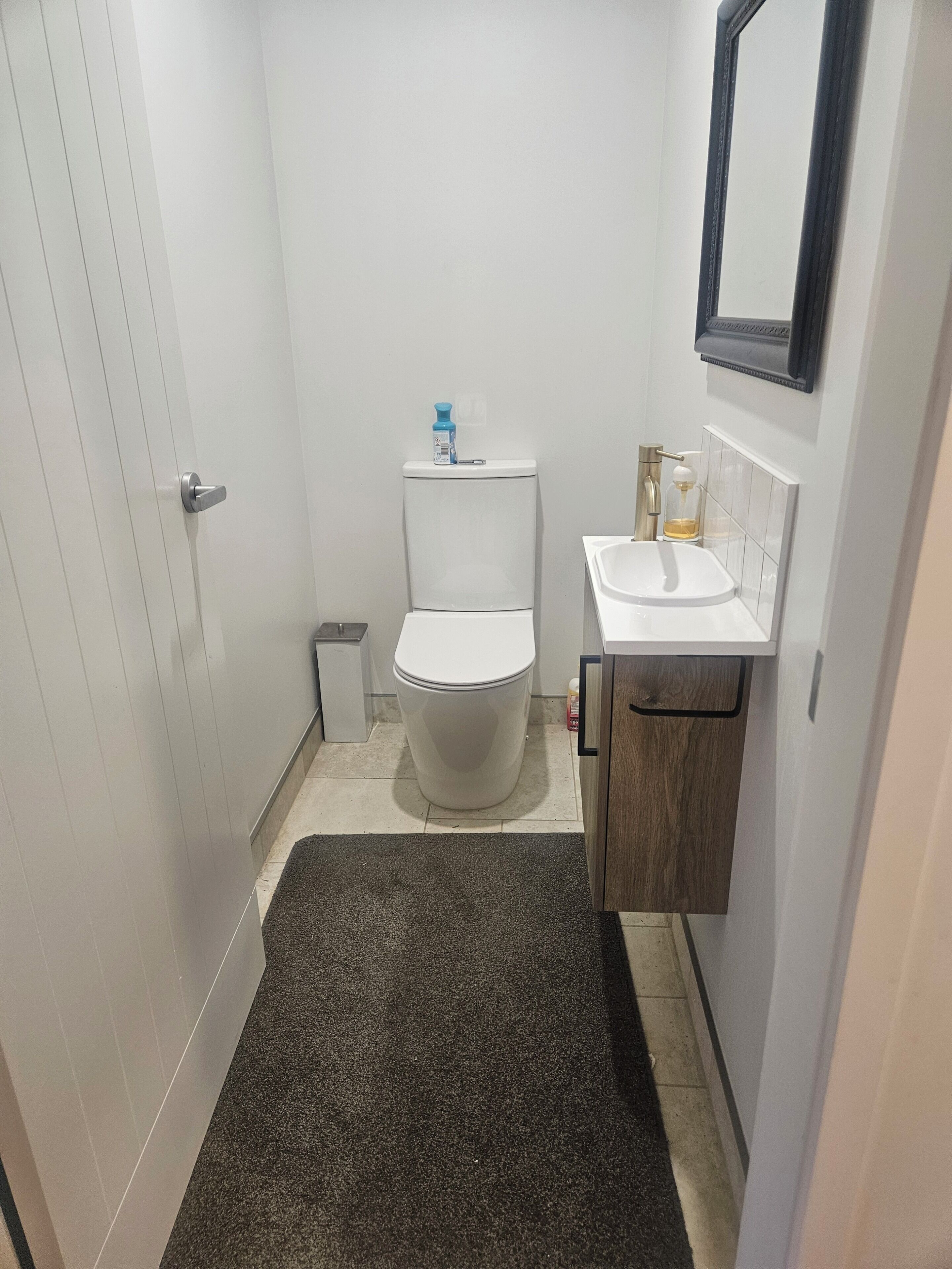 Une petite salle de bain comprenant des toilettes, un lavabo et un miroir au-dessus.