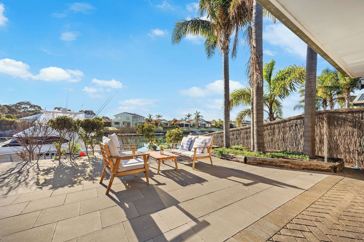 Une terrasse extérieure avec une piscine, des chaises longues et des palmiers.