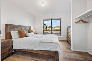 A bedroom with a large bed, wooden headboard, and a view through a sliding door.