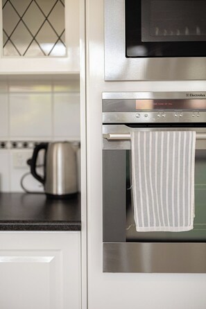 A kitchen with a microwave, oven, and kettle.