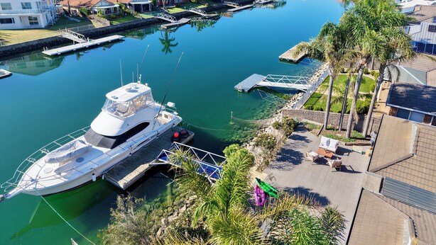 Ein Yachthafen mit einer dort vertäuten Yacht, klarem Wasser und Wohnhäusern im Hintergrund.