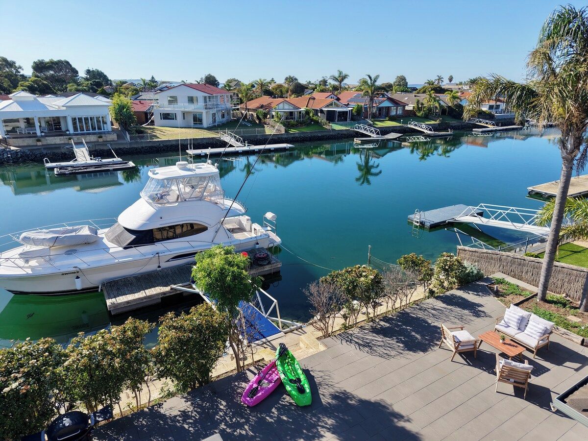 Un port de plaisance avec des bateaux amarrés, un petit quai et un espace extérieur aménagé avec du mobilier de jardin.
