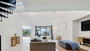 Ein modernes Wohnzimmer mit einer Couch, einem Couchtisch, einem Fernseher und einem großen Fenster mit Blick ins Freie.