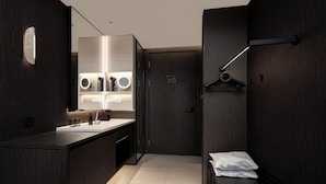 A modern bathroom with a dark wood finish, a large mirror, a sink with a countertop, and a towel rack.
