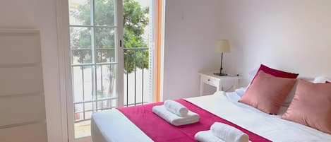 A hotel room with a bed, a nightstand, a lamp, and a view through a sliding door.