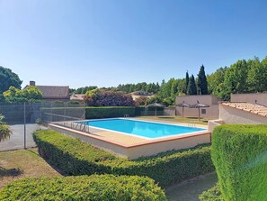 A rectangular swimming pool surrounded by neatly trimmed hedges, with a clear blue sky above and a fence enclosing the area. - Tennis Résidence by Interhome (Saint Cyprien)