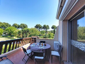 Un balcone con tavolo apparecchiato per due persone, sedie e vista su un giardino.