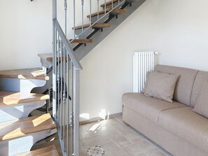 A staircase with wooden steps and metal railings, a beige sofa, and a radiator. - Il Borghetto di Castagnole by Interhome (Castagnole Monferrato)