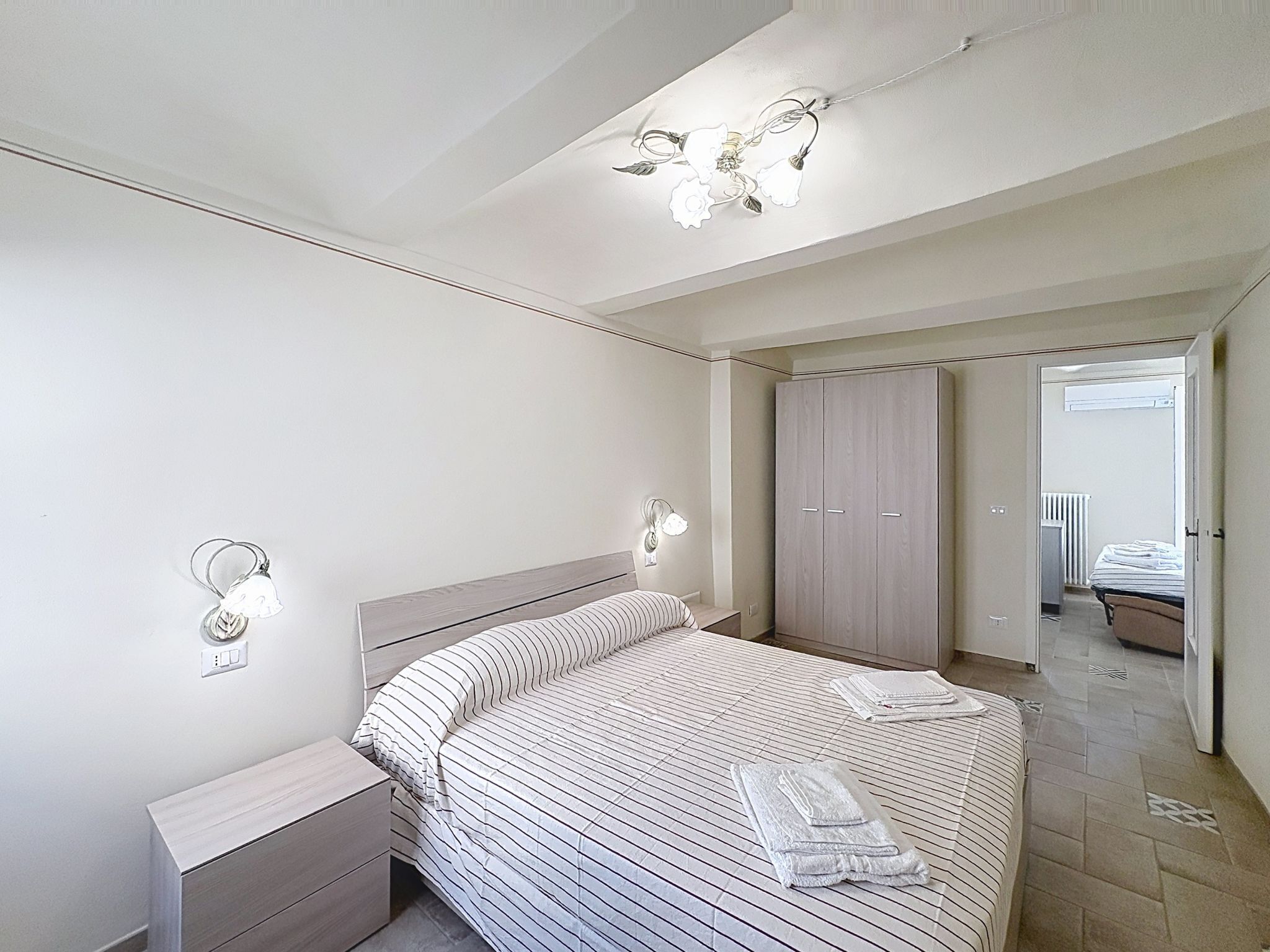 Een slaapkamer met een bed, nachtkastjes, een kledingkast en een badkamer die door een open deur zichtbaar is.