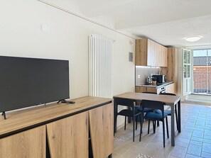 Una cocina moderna con armarios de madera, microondas integrado y comedor con mesa y sillas.
