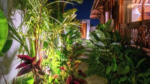 A tropical garden pathway leading to a wooden structure with a thatched roof. - Pondok Langkih Pool Villa (Gianyar)