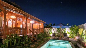 A poolside area with a wooden structure, a pool, and outdoor seating. - Pondok Langkih Pool Villa (Gianyar)
