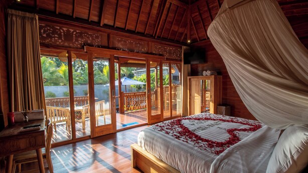 A wooden room with a bed, a desk, and a view of the outdoors. - Pondok Langkih Pool Villa (Gianyar)