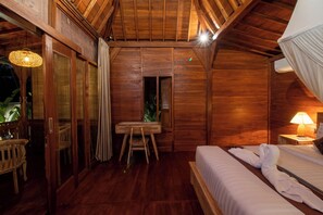 Een kamer met houten vloer, een bed, een tafel en een stoel.