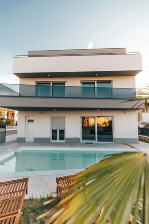 A modern two-story house with a swimming pool, a balcony, and a sliding glass door. - Villa Aura Vir (Vir)