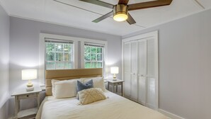 Ein Schlafzimmer mit einem Bett, Nachttischen, einem Deckenventilator und einem Fenster.