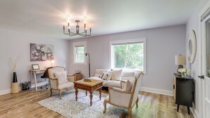Ein Wohnzimmer mit Sofa, Sesseln, einem Couchtisch, einer Kronleuchter und einem Schreibtisch.