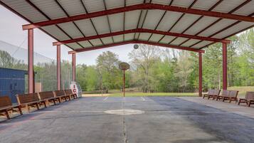 Ein Basketballplatz mit Bänken, einem Korb und einem überdachten Sitzbereich.