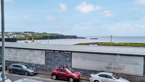 Uitzicht op de kust, met een weg, geparkeerde auto's en een gebouw met een stenen gevel.