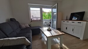 A living room with a sofa, a coffee table, a TV, and a sliding glass door leading to a patio.