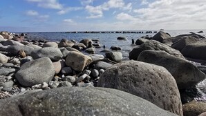 A rocky shoreline with large boulders and a distant pier.