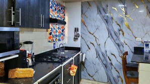 A kitchen with dark cabinets, a marble backsplash, a gas stove, a microwave, and a sink. - LPW STORE SARIE BAY No. 01 (san Andrés islas, colombia)