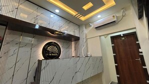 Zona de recepción de hotel con un mostrador de mármol, un letrero de recepción y un cartel con el número de recepción.