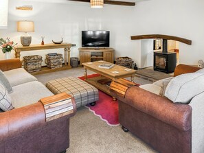 Ett mysigt vardagsrum med en soffa, ett soffbord, en tv och en öppen spis.