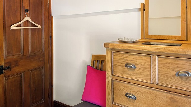 Een houten dressoir met lades, een spiegel en een klein bordje erboven.