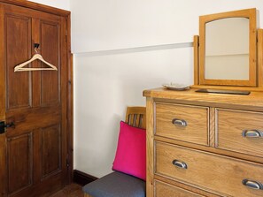 A wooden dresser with drawers, a mirror, and a small plate on top.