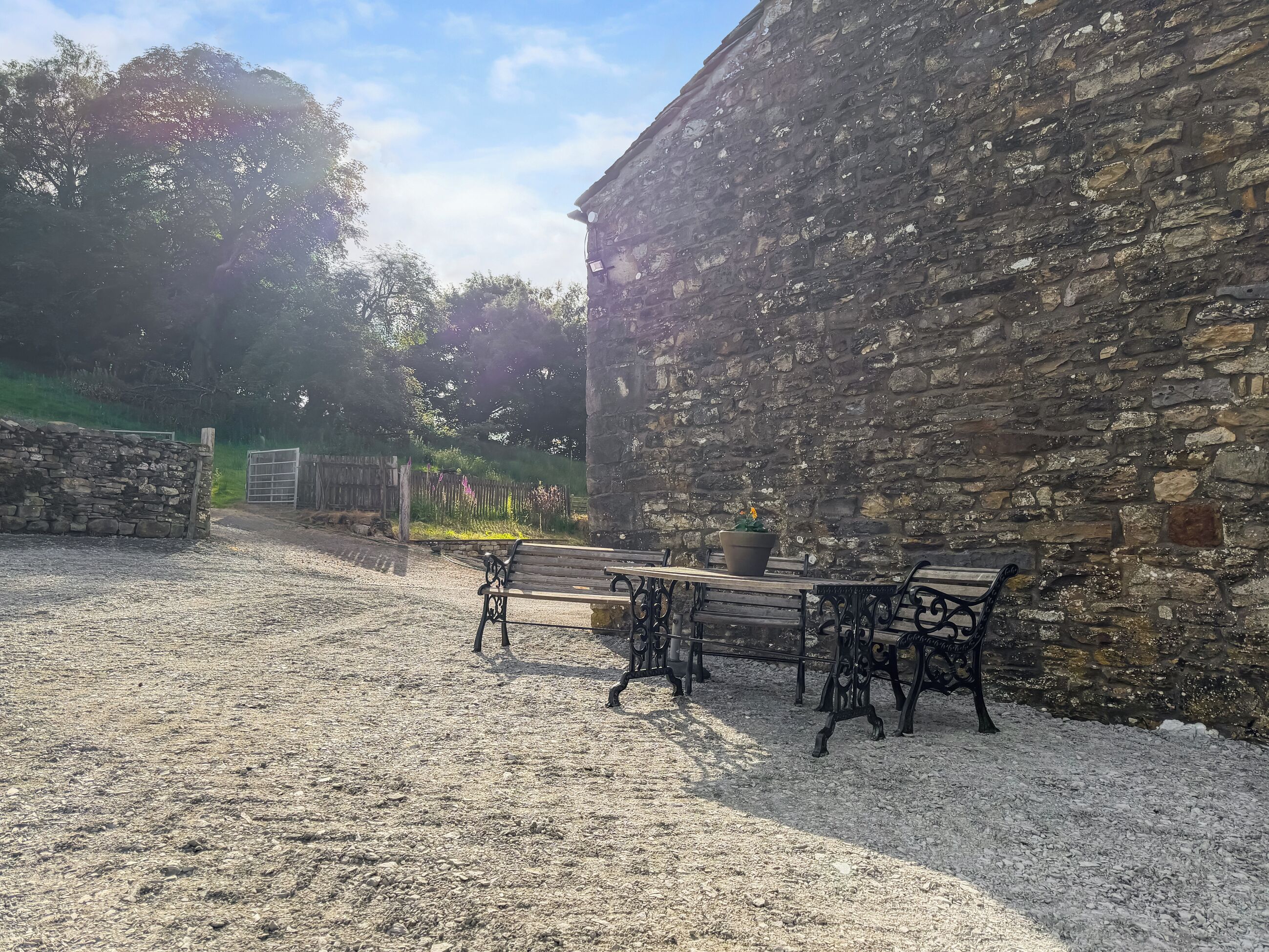 An outdoor area with stone walls, gravel ground, and benches.