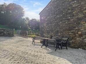 An outdoor area with stone walls, gravel ground, and benches.