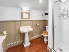 A bathroom with a pedestal sink, toilet, and a glass shower enclosure.