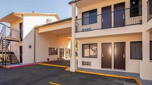 Ett hotell med flera våningar, balkonger, en överbyggd entré och en parkeringsplats.