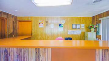 A reception area with a wooden panel wall, a reception desk, and a clock on the wall.