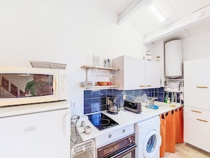A compact kitchen with a microwave, stove, oven, and washing machine. - L'île des Marinas by Interhome (Cap d'Agde)