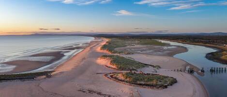 Un paysage côtier avec une plage de sable, une rivière et un pont.