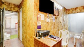 A room with a wooden desk, a television mounted on the wall, and a chair. - Classic Vishnu's Galaxy Rooms (Chennai)