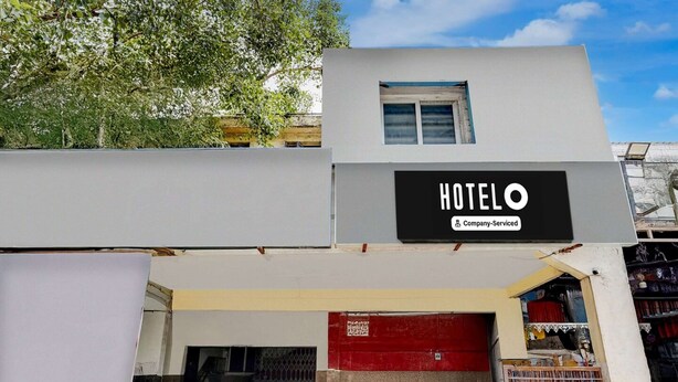 A hotel with a sign indicating it is company-serviced. There is a red door and a staircase leading to the entrance. - Classic Vishnu's Galaxy Rooms (Chennai)