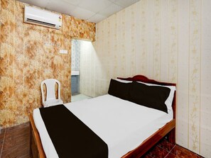 Ein Hotelzimmer mit Bett, Klimaanlage, Stuhl und einem durch eine Tür sichtbarem Badezimmer.