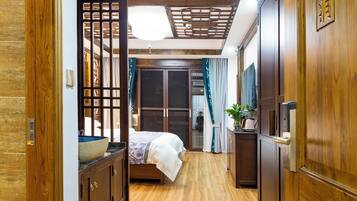 A bedroom with a bed, wooden wardrobe, and a small table with a plant.