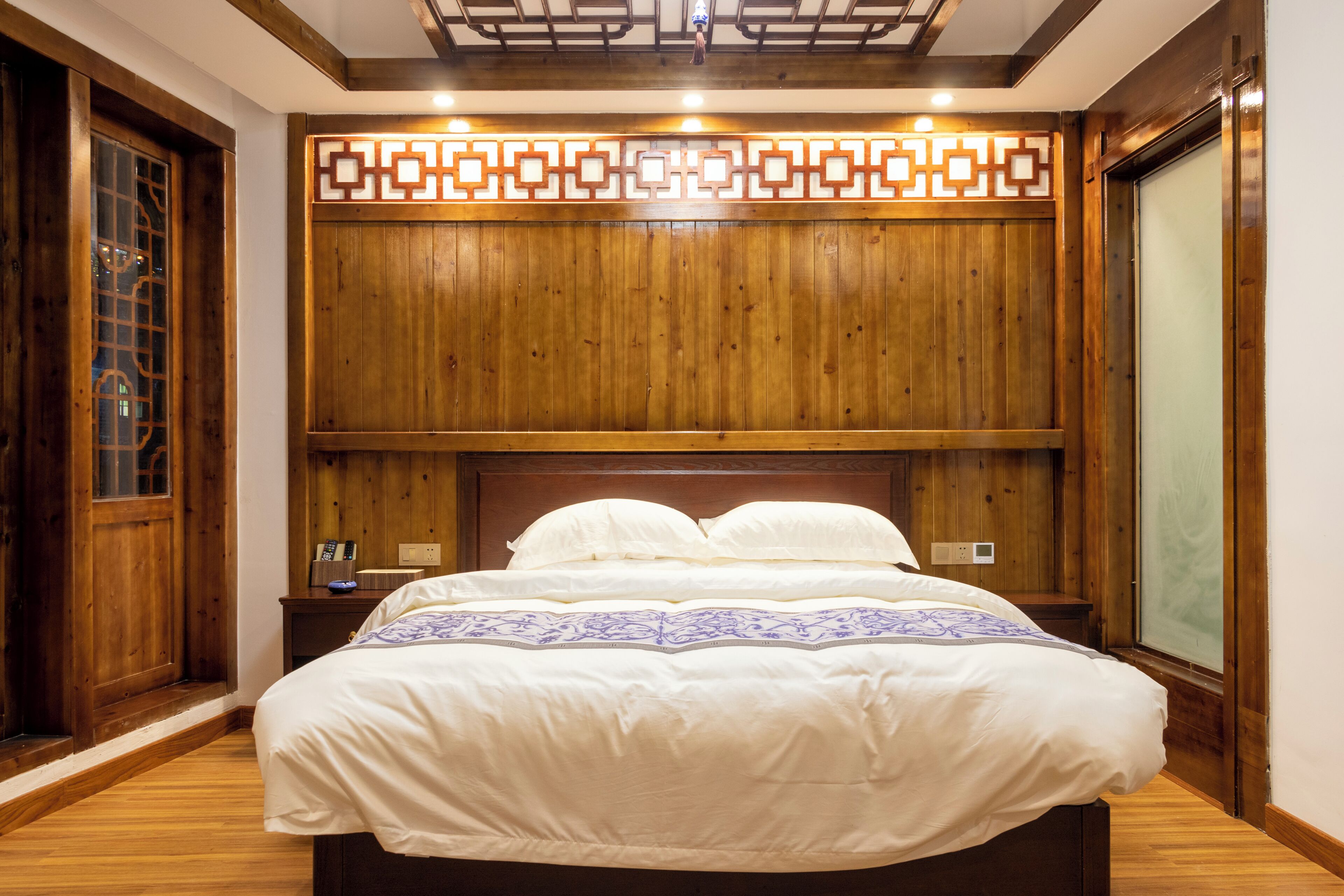 A wooden-paneled room with a large bed, a nightstand, and a window with a view.