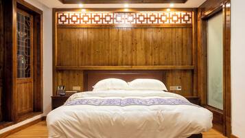 A wooden-paneled room with a large bed, a nightstand, and a window with a view.